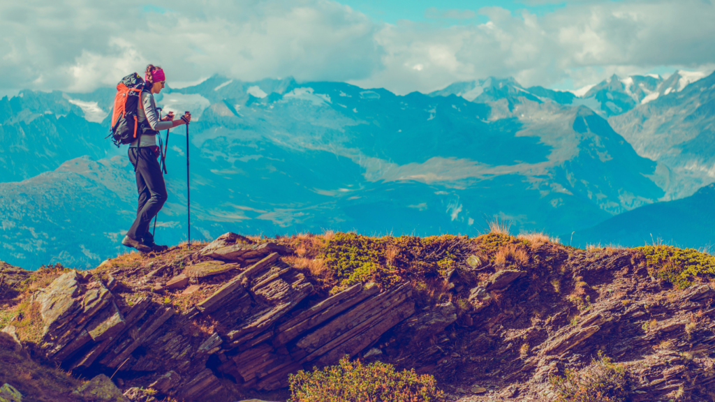 A lone female trekker on a hilltop gazing at the clear blue skies